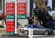 A commuter drives past a gas station signage displaying current prices for self serve and full serve gasoline in La Jolla, California March 8, 2012. REUTERS/ Mike Blake