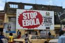 People walking past a billboard with a message about Ebola in Freetown, Sierra Leone, on November 7, 2014