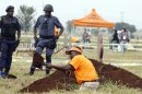 National Prosecuting Authority worker digs up a grave for exhumation of two bodies, that are believed be those of young activists as police officer watch at Avalon Cemetery in Johannesburg, South Africa, on Tuesday, March 12, 2013. Forensic scientists on Tuesday exhumed two bodies believed to belong to young activists last seen 24 years ago at the home of Winnie Madikizela-Mandela, a discovery that has forced a new police murder investigation. (AP Photo/Themba Hadebe)