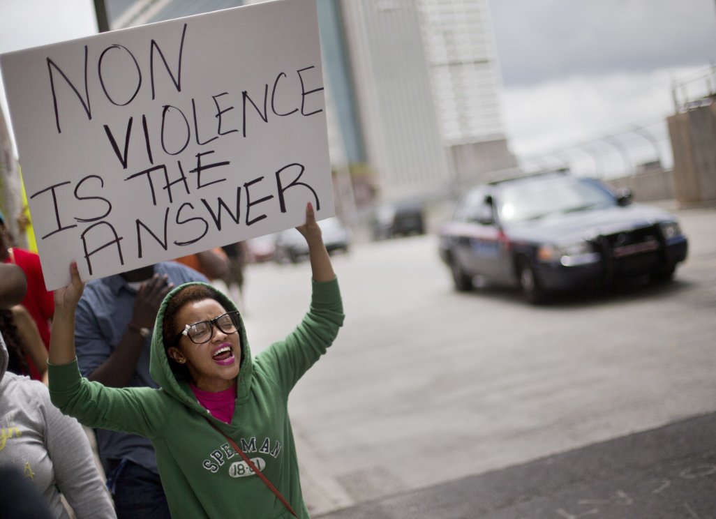 Tabatha Holley, de 19 años, corea consignas en una marcha de protesta al día siguiente que un jurado de Florida absolvió al vigilante voluntario George Zimmerman en la muerte a tiros del joven Trayvon Martin, el domingo 14 de julio de 2013, en Atlanta. El cartón dice: "La no violencia es la respuesta". (Foto AP/David Goldman)