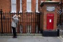 A man drinks from a can of Coke near a post box in London