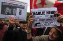 People hold up signs during a demonstration to protest against the disappearance of two Tunisian journalists, and the attack in Paris on satirical French newspaper Charlie Hebdo, in Tunis