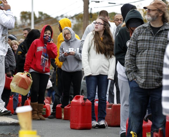 As temperatures begin to drop, people wait in line to fill containers with gas at a Shell gasoline filling station Thursday, Nov. 1, 2012, in Keyport, N.J. In parts of New York and New Jersey, drivers lined up Thursday for hours at gas stations that were struggling to stay supplied. The power outages and flooding caused by Superstorm Sandy have forced many gas stations to close and disrupted the flow of fuel from refineries to those stations that are open. (AP Photo/Mel Evans)