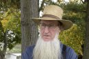 FILE- In anan Oct. 10. 2011 file photo, Sam Mullet Sr., the leader of a breakaway Amish group stands in the front yard of his Bergholz, Ohio home. A federal judge is weighing the government's request to require the suspect in beard- and hair-cutting attacks against fellow Amish in Ohio to hire a private attorney. Federal prosecutors said in a court filing last week that Sam Mullet Sr. recently received more than $2 million from gas and oil leases on his property. ( AP Photo/File-Amy Sancetta)