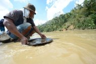 A miner pans for gold at a river near the typhoon disaster zone in Mawab town, Compostela Valley province, on December 9. Numerous small, illegal or poorly regulated gold mines dot its slopes and the local government says they provide 40% of the province's economic output