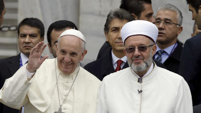 Pope Francis waves to journalists as he stands by Istanbul Mufti Rahmi Yaran upon their arrival to the Blue Mosque in Istanbul, Turkey, Saturday, Nov. 29, 2014. Pope Francis visits two of Turkey's most iconic sites and shifts gears toward more religious affairs as he arrives in Istanbul for the second leg of his three-day visit to the Muslim nation. The Vatican says Francis will tour Istanbul's Sultan Ahmet mosque on Saturday and pause for a moment of "reflection." (AP Photo/Thanassis Stavrakis)