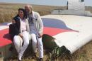 Jerzy Dyczynski and Angela Rudhart-Dyczynski whose daughter, 25-year-old Fatima, was a passenger on Malaysia Airlines flight MH17, sit on part of the wreckage of the crashed aircraft in Hrabove, Ukraine, Saturday, July 26, 2014. The couple who live in Perth, Australia, crossed territory held by pro-Russian rebels to reach the wreckage-strewn farm fields outside the village of Hrabove. They last spoke to Fatima shortly before she boarded the flight for Kuala Lumpur in Amsterdam on July 17. Rudhart-Dyczynski said, "We have promised our daughter we will come here." (AP Photo/Nicholas Garriga)