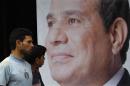 People walk past a poster of presidential candidate Abdel Fattah al-Sisi at one of his campaign headquarters in Cairo