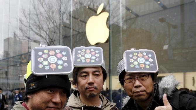 Men wearing cardboard hats depicting the Apple Watch, pose for photos before it goes on display in front of the Apple Store in Tokyo's Omotesando shopping district