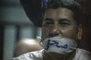 Egyptian journalist Ibrahim al-Darawi has his mouth covered with a cloth gag reading in Arabic "Journalist" as he and others stand trial in Cairo on June 2, 2015
