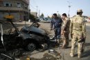 Security forces inspect the scene of a car bomb attack in Kirkuk, 290 kilometers (180 miles) north of Baghdad, Iraq, Thursday, Aug 16, 2012. Five separate bombings in central and northern Iraq, killed and wounded scores of people early Thursday, police said. (AP Photo/Emad Matti)