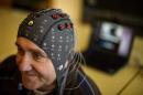 A patient wears a cap with electrods next to a computer during a presentation of brain-machine interface on January 23, 2013 in Sion, Switzerland