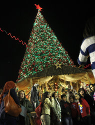 Un grupo de palestinos se toma una fotografía frente a un árbol de navidad en la Plaza Manger, afuera de la Basílica de la Natividad, en el poblado de Belén, Cisjordania, el domingo 23 de diciembre de 2012. (Foto AP/Adel Hana)