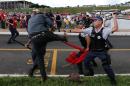 A demonstrator clashes with military police officers during a protest in Brasilia, Brazil, Tuesday, April 7, 2015. Thousands of workers have staged rallies in 12 cities across Brazil to protest against a proposed law that would allow companies to outsource their labor force. The biggest rally occurred in Brasilia where some 3,000 demonstrators gathered in front of Congress hours before lawmakers were expected to vote on the law. (AP Photo/Eraldo Peres)