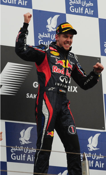 German driver Sebastian Vettel celebrates on the podium on April 22, 2012 at the Bahrain International circuit in Manama after fending off returning former champion Kimi Raikkonen to win the Gulf kingdom's Grand Prix for the Red Bull driver's first victory of 2012. AFP PHOTO/TOM GANDOLFINI (Photo credit should read Tom Gandolfini/AFP/Getty Images)