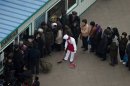A food shop keeper sweeps with a broom while people line up outside a shop window in Pyongyang, North Korea, Tuesday, April 16, 2013. (AP Photo/Alexander F. Yuan)