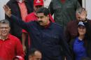 Venezuela's President Nicolas Maduro, waves to supporters, nexto to lawmaker Elias Jaua, left, and first lady Cilia Flores, right, during a demonstration at Miraflores presidential Palace, in Caracas, Venezuela, Thursday, April 14, 2016. Several thousand public employees and government supporters marched to protest against a new law that hands over legal property titles to the beneficiaries of government housing programs. (AP Photo/Ariana Cubillos)
