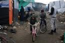 FILE - In this Feb. 25, 2016 file photo, Afghan children ride their bicycles in a makeshift migrants camp near Calais, France. The U.K. government said on Monday, Oct. 10, 2016 that within days, Britain will begin admitting hundreds of children from a border refugee camp on the French side of the English Channel. (AP Photo/Jerome Delay, File)