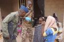 In this photo made available by the Nigerian Military taken Wednesday, April 29, 2015, a Nigerian soldier speaks to woman and children that were allegedly rescued by the Nigerian Military after being taken by Islamic extremists in Sambisa Forest, Nigeria. Scores more women and children have been rescued from Islamic extremists in the remote Sambisa Forest, Nigeria's military said amid reports that some of the women fought their rescuers fiercely. (Nigerian Military via AP)