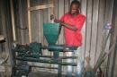 A worker pushes material through a pulverising machine, as the dried garbage is then turned into bio-charcoal on September 4, 2015 in Douala, Cameroon