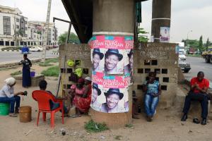 Workers sit beside campaign posters of Nigerian President …