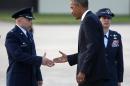 President Barack Obama presents a presidential challenge coin to U.S. Air Force Col. Douglas Mellars, left, accompanied by U.S. Air Force Col. Angela Cadwell, as he arrives at Royal Air Force Station Fairford, Wednesday, Sept. 3, 2014, to attend the NATO Summit in Wales. (AP Photo/Charles Dharapak)