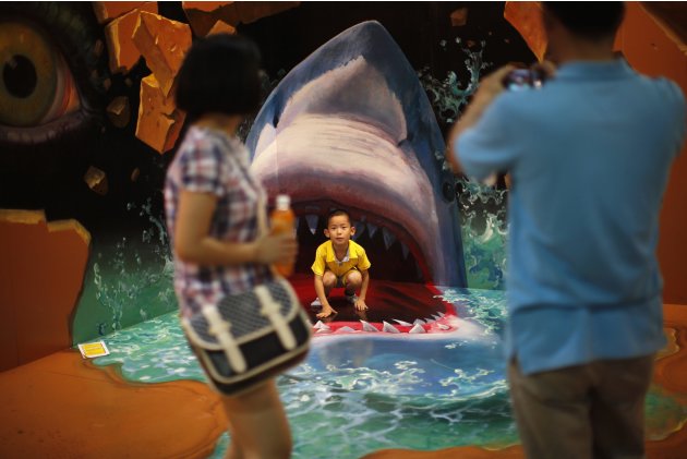 Boy poses for a photograph in front of a 3D painting at 2012 Magic Art Special Exhibition in Hangzhou