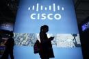 A visitor walks past a Cisco advertising panel as she looks at her mobile phone at the Mobile World Congress in Barcelona