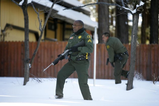 San Bernardino County Sheriff's officers Ken Owens, center, and Bernabe Ortiz search a home for former Los Angeles police officer Christopher Dorner in Big Bear Lake, Calif, Sunday, Feb. 10, 2013. The hunt for the former Los Angeles police officer suspected in three killings entered a fourth day in snow-covered mountains Sunday, a day after the police chief ordered a review of the disciplinary case that led to the fugitive's firing and new details emerged of the evidence he left behind. (AP Photo/Jae C. Hong)
