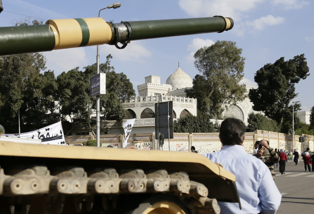 An Egyptian protester takes a picture with his mobile of another in front of an Egyptian army tank outside the presidential palace, background, in Cairo, Egypt, Saturday, Dec. 8, 2012. Egypt's military has warned of 'disastrous consequences' if the political crisis gripping the country is not resolved through dialogue. (AP Photo/Hassan Ammar)