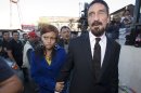 Software company founder John McAfee, right, accompanied by his girlfriend "Sam," leaves after a press conference outside the Supreme Court in Guatemala City, Tuesday, Dec. 4, 2012. McAfee, 67, who has been identified as a "person of interest" in the killing of his neighbor in Belize, 52-year-old Gregory Faull, has surfaced in public for the first time in weeks, saying Tuesday that he plans to ask for asylum in Guatemala because he fears persecution in Belize. (AP Photo/Moises Castillo)