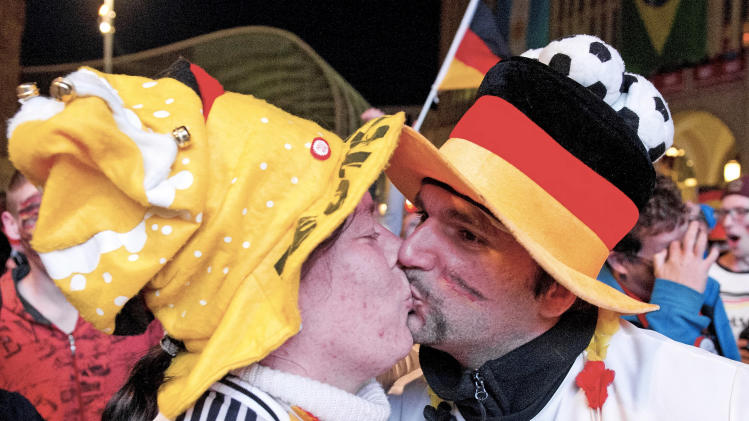German soccer fans kiss after the kick off of their team during the soccer World Cup 2014 match Germany vs Ghana at a public viewing zone in Chemnitz, central Germany, Saturday, June 21, 2014. (AP Photo/Jens Meyer)