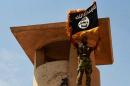 An image made available on the jihadist website Welayat Salahuddin on June 11, 2014 shows an ISIL militant posing with the Islamist flag after they allegedly seized an army checkpoint in the northern Iraqi province of Salahuddin