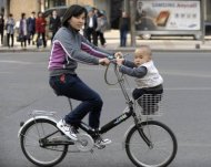Uma chinesa e seu filho passeiam de bicicleta, em Pequim