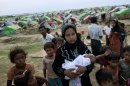 In this May 13, 2013 photo, an internally displaced Rohingya woman holds her newborn baby surrounded by children in the foreground of makeshift tents at a camp for Rohingya people in Sittwe, northwestern Rakhine State, Myanmar. Authorities in Myanmar's western Rakhine state have imposed a two-child limit for Muslim Rohingya families, a policy that does not apply to Buddhists in the area and comes amid accusations of ethnic cleansing in the aftermath of sectarian violence. (AP Photo/Gemunu Amarasinghe)