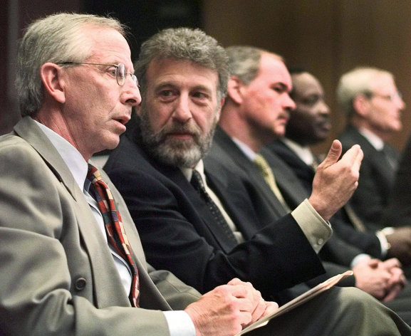 FILE - In this Thursday, May 6, 1999 file photo, George Zimmer, second from left, gestures to Andy Dolich prior to a meeting, in Oakland, Calif. Men's Wearhouse Inc. says it has dismissed Zimmer, its founder and executive chairman. In a terse release issued Wednesday, June 19, 2013, the company didn't give a reason for the abrupt firing of Zimmer, who built Men's Wearhouse from one small Texas store using a cigar box as a cash register to one of the nation's largest specialty retailers in men's clothing, with 1,143 locations. (AP Photo/Ben Margot, File)