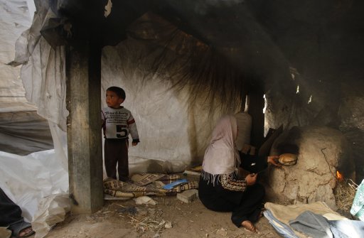 A Palestinian woman bakes bread in a wood-fired oven inside her tent in the northern Gaza Strip