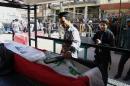 An Iraqi policeman uses a bomb detector device to examine the flag-draped coffin of a man who was killed in a bombing during his funeral procession in the Shiite holy city of Najaf, 100 miles (160 kilometers) south of Baghdad, Iraq, Thursday, March 20, 2014. A suicide bomber struck inside a Baghdad cafe overnight where customers were watching a football game on TV, killed and wound scores of people, Iraqi officials said Thursday. (AP Photo/Jaber al-Helo)