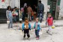 Syrian children stand outside a community kitchen in the Salhin district of the northern city of Aleppo on November 15, 2014