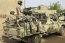 Nigerian soldiers hold their weapons as they sit on a military pick-up truck at their base in the town of Banamba