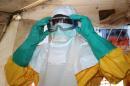 File photo taken on June 28, 2014 shows a member of Doctors Without Borders (MSF) putting on protective gear at the isolation ward of the Donka Hospital in Guinea's capital Conakry, where people infected with the Ebola virus are being treated