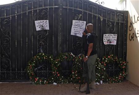 A Libyan government militia guarding the main entrance of the U.S. consulate that was attacked last week, fixes a note written by Libyans against the attack, in Benghazi city September 18, 2012. REUTERS/Asmaa Waguih