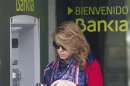 A woman uses an ATM cash point machine at a branch of the Bankia bank in Madrid Thursday May 17, 2012. A recently nationalized Spanish bank's shares plummeted Thursday after a newspaper said depositors were rushing to withdraw money, while the country paid sharply higher interest rates in a debt auction, reflecting concerns the country will be caught up in the fallout of the Greek crisis. Logo says ' Welcome to Bankia'. (AP Photo/Paul White)