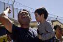 Daniel Rodriguez holds three-year-old Matthew Huert as he leads a chant for members of the group Border Dreamers and other supporters of an open border policy who marched to the United States border Monday, March 10, 2014, in Tijuana, Mexico. (AP Photo/Lenny Ignelzi)