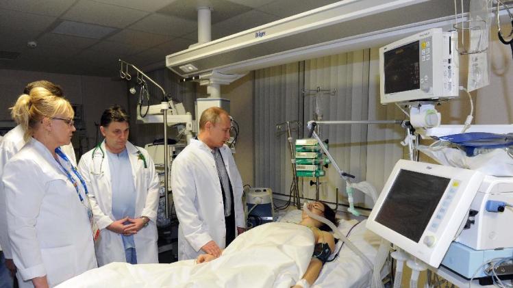 In this photo provided by RIA Novosti Kremlin, Russian President Vladimir Putin, center, speaks to skier Maria Komissarova in a hospital in Krasnaya Polyana, Russia, on Saturday, Feb. 15, 2014. The 23-year-old Russian ski cross racer fractured her spine during a training session Saturday and underwent a 6 1/2 hour surgery. (AP Photo/RIA Novosti, Mikhail Klimentyev, Presidential Press Service)