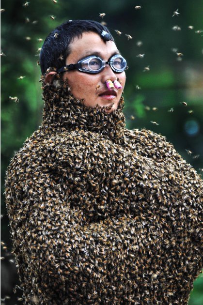 In this photo released by Xinhua News Agency, 42-year-old beekeeper Wang Dalin is covered with bees during a contest against 20-year-old Lu Kongjiang, also a beekeeper, in Longhui County of Shaoyang C