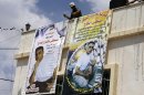 Relatives of Mustafa al-Haj hang banners showing him in the village of Brukin, south of Nablus, in the West Bank, Monday, Aug. 12, 2013. Al-Haj is one of the 26 Palestinian prisoners, most of them held for deadly attacks, Israel agreed to release this week as part of a U.S.-brokered deal that led to a resumption of Mideast negotiations. (AP Photo /Nasser Ishtayeh)