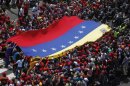 Supporters of Venezuela's late President Hugo Chavez stretch out a national flag as they gather to see his coffin driven through the streets of Caracas