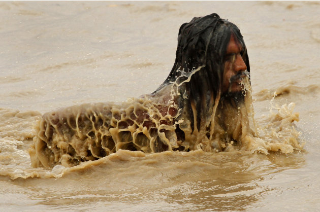 A Hindu holy man takes a dip in the River Ganges, which appears muddy and swollen after heavy rains in upstream areas, in Allahabad, Thursday, June 30, 2011. (AP Photo/Rajesh Kumar Singh)