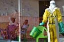 A health worker walks towards patients under quarantine at the Nongo Ebola treatment centre in Conakry, Guinea on August 21, 2015